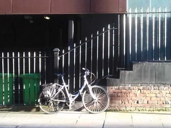 Photograph of a silver bicycle glowing in the sun so it appears white