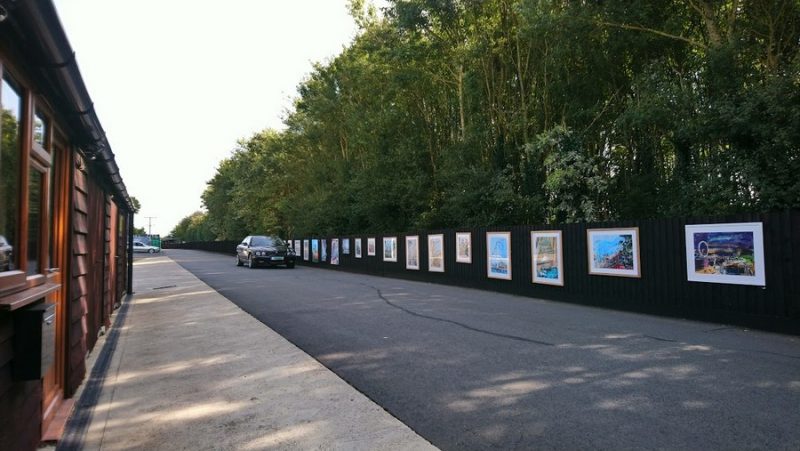Black Jaguar car driving past an open air art exhibition